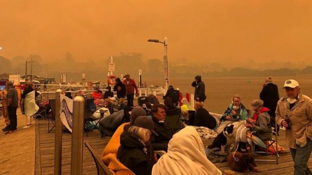 Gente a la espera en el embarcadero mientras el cielo se vuelve anaranjado