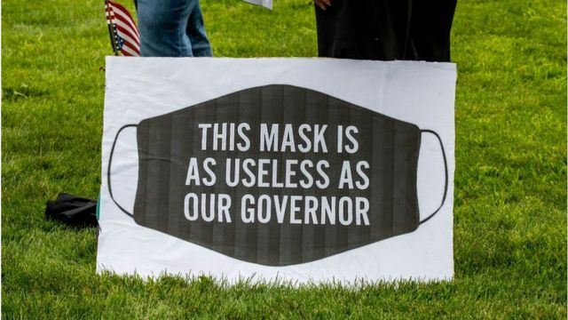 Esta pancarta dice: "Las mascarillas son tan inútiles como nuestro gobernador" y la llevaba una manifestante en una movilización en Minessota.