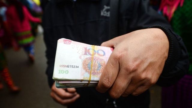 Hình minh họa một người cầm tiền Trung Quốc tại Mèo Vạc, một huyện miền núi biên giới giữa tỉnh Hà Giang của Việt Nam và Trung Quốc làm mai mối kết hôn hoặc hứa hẹn công việc ở Trung Quốc