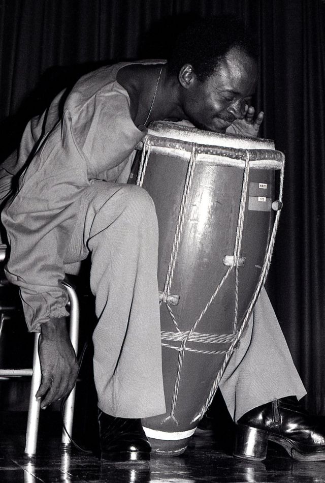 Un percusionista aprieta el mentón contra el cuero de un tambor