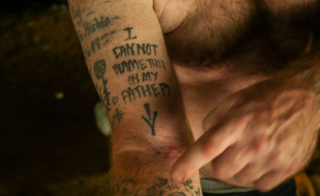 Un tatuaje que dice: "No puedo culpar a mi padre de esto", y señala una cicatriz de aguja vieja.