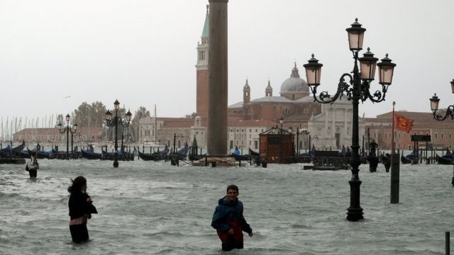 People walk in flooded St Mark Square in Venice on 29 October 2018