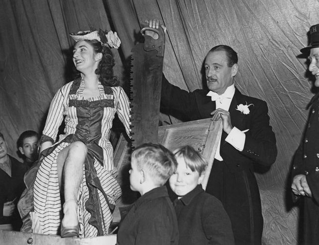 El mago británico Jasper Maskelye se prepara para aserrar a su asistente, Maisie Wright, en Londres en 1948