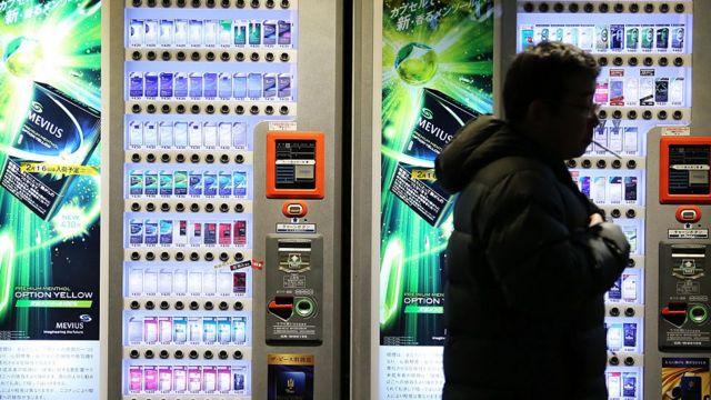 Homem fumando no Japão em frente a máquinas que vedem cigarros