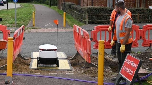 An autonomous robot called Starship travels along a path under construction on its way to deliver groceries from a nearby Co-op supermarket in Milton Keynes, England on September 20, 2021.