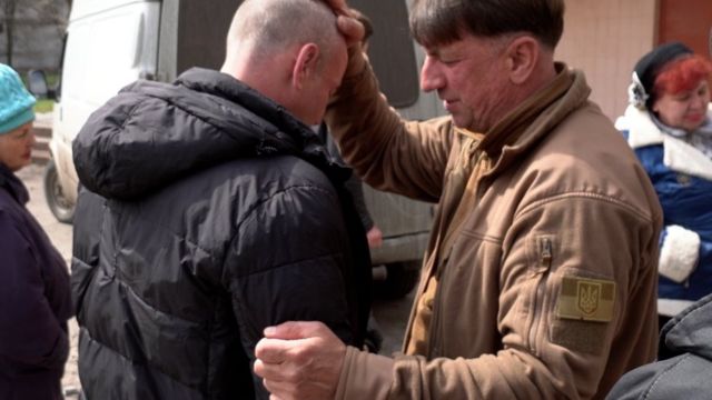 Un pastor ucraniano pone la mano sobre la cabeza de un hombre