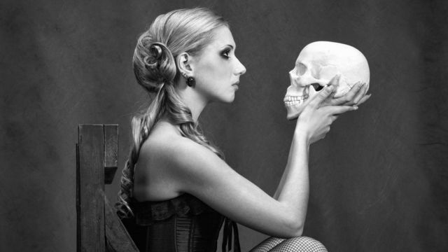 Mujer interpreta a Hamlet con una calavera en la mano.