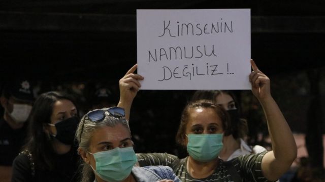 "kimsenin namusu değiliz" pankartı taşıyan bir kadın