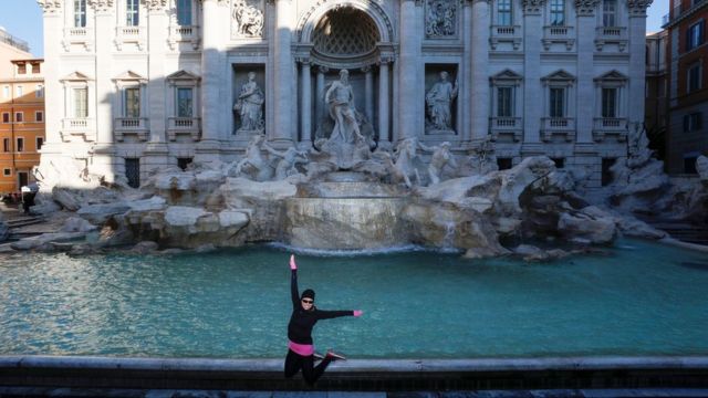 Una mujer posa frente a la Fontana di Trevi en Roma.