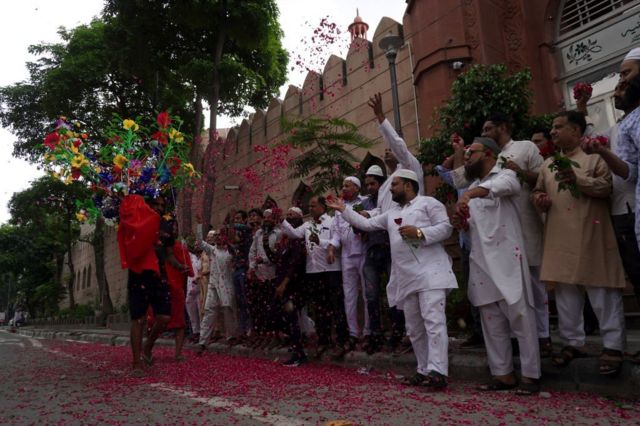 مسلمون يرمون الورود على مصلين هندوس يحملون مياهاً مقدسة من نهر الغانج، خلال شعائر الحج السنوية "كانوار ياترا" احتفالاً بالإله شيفا، في نيو دلهي، في يوليو/ تموز 2022