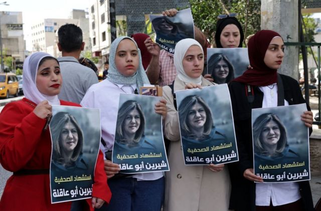 متظاهرات فلسطينيات يرفعن صور شيرين أبو عاقلة وقد كتب عليها "استشهاد الصحفية شيرين أبو عاقلة"