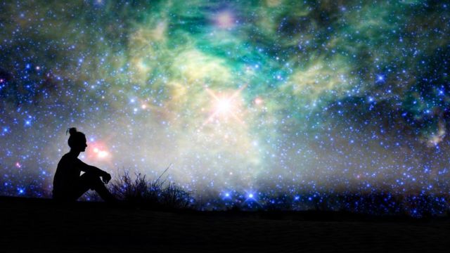 Silhouette of a woman sitting outside, starry night background