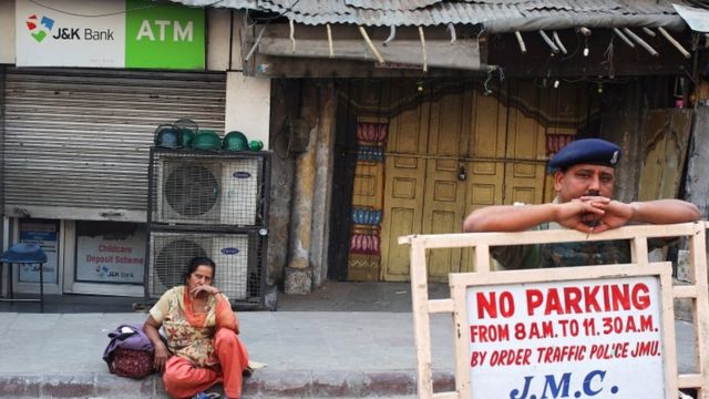 ज्म्मू में पैसे के लिए एक एटीएम के बाहर बैठी महिला.