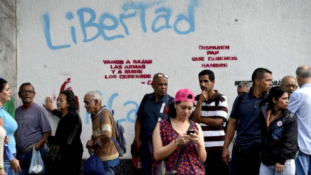 Una fila de personas espera que llegue el autobús en Caracas.