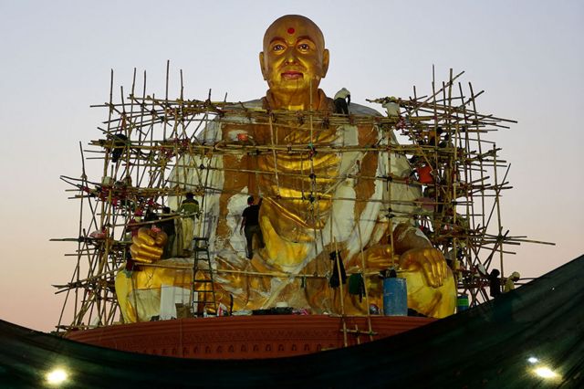 عمال يضفيون اللمسات الأخيرة على تمثال كبير لبراموخ سوامي مهراج، قبل الاحتفالات المئوية لميلاد المعلم الهندوسي، في أرض المهرجانات في ضواحي أحمد آباد ، الهند.