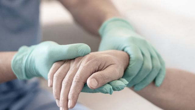 Un profesion al de la salud toma la mano de un paciente