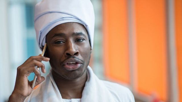 A man in traditional Sudanese clothing speaks on the phone