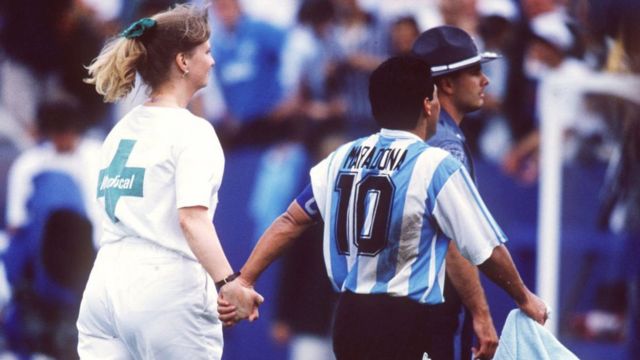 Maradona em campo ao lado de uma enfermeira