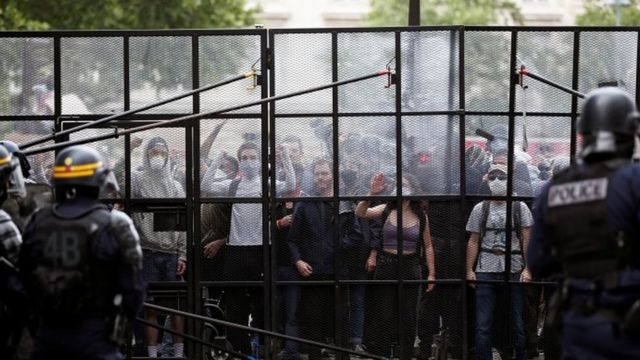 Demonstrators are seen behind a fence as they protest against police brutality and the death in Minneapolis police custody of George Floyd, at the Place de la Republique square in Paris 13 June