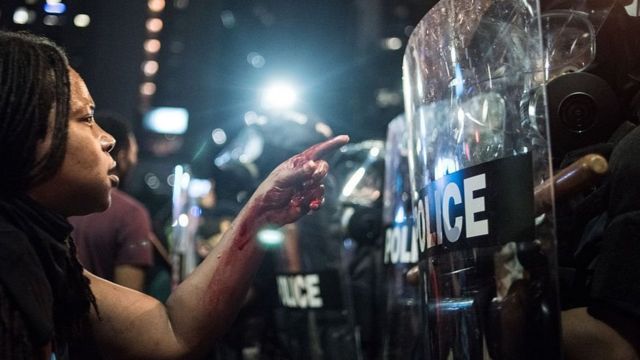 Black Lives Matter protester in front of a line of riot police