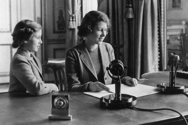 Первое радиообращение принцессы Елизаветы. Рядом с нею стоит ее сестра, принцесса маргарет, 12 октября 1940 года в Лондоне.