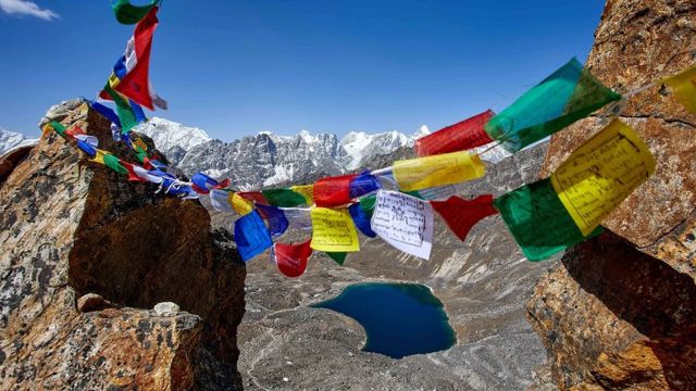 Picos no Himalaia com bandeiras coloridas com escritos tibetanos