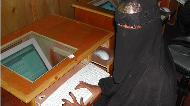 A woman wearing a niqab types at a computer in an internet cafe in Somalia
