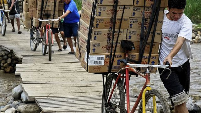 PEssoas carregando caixas em bicicletas