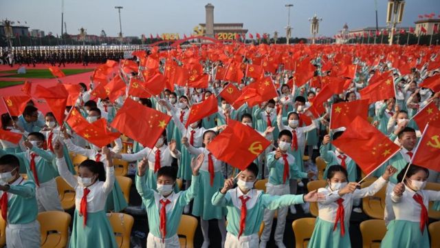 estudiantes ondean banderas de China y del PCCh en Pekín el 1 de julio, en la plaza de Tiananmen.
