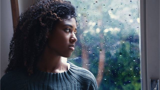 Woman who looks sad stares out window