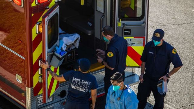 Trabajadores de la salud se preparan para sacar un paciente en camilla de una ambulancia