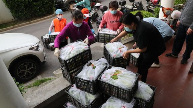 Voluntarios entregando suministros de alimentos gratuitos a los residentes de una comunidad cerrada.