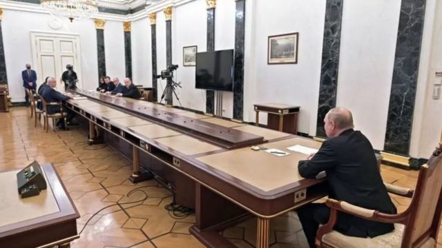 Putin sentado em mesa durante reunião