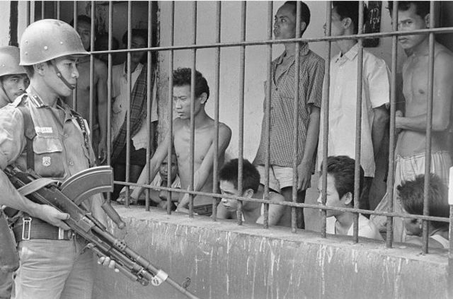 Serdadu mengawasi para tersangka Komunis yang ditahan di sebuah lokasi di Tengerang, oktober 1965