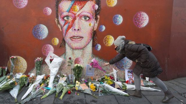 Mulher deposita flores em mural em homenagem a David Bowie em Londres