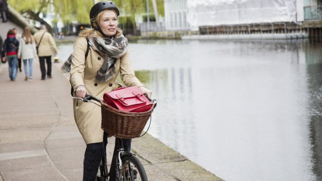 امرأة تركب دراجتها إلى العمل بمحاذاة قناة مائية.