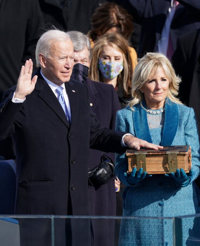 President Biden places his hand on a large Bible