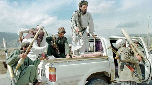 Taliban militia fighters climb aboard their Toyota pickup with RPG-7 anti-tank rocket launchers and assault rifles.
