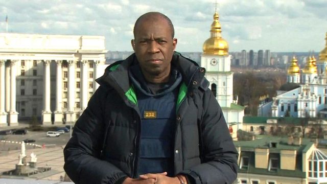 Clive Myrie, reporter da BBC, um homem negro e careca usando roupas de frio