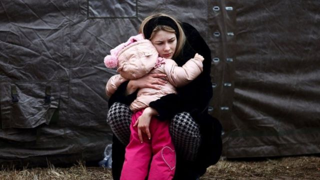 A Ukrainian woman fleeing Russian invasion hugs a child at a temporary camp in Przemysl, Poland