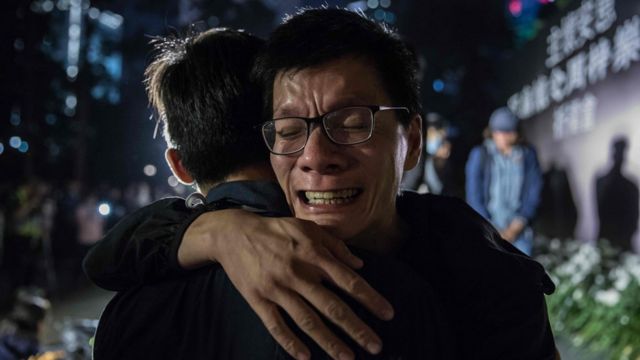 A man cries after laying a flower during a vigil in Hong Kong on 10 November, 2019, in memory of university student Alex Chow