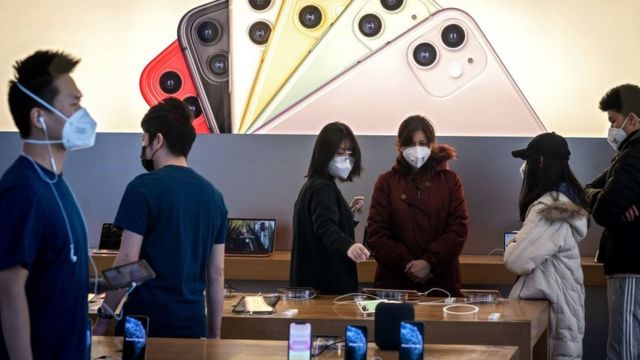 Personal y clientes de Apple con máscaras en una tienda en Pekín.