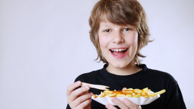 Niño comiendo papas fritas con kétchup