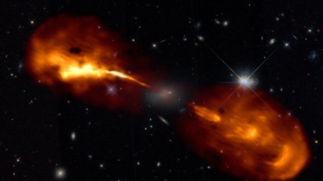 Надмасивна чорна діра в центрі галактики, яку ледь видно в центрі зображення, викидає потужні струмені речовини в космос