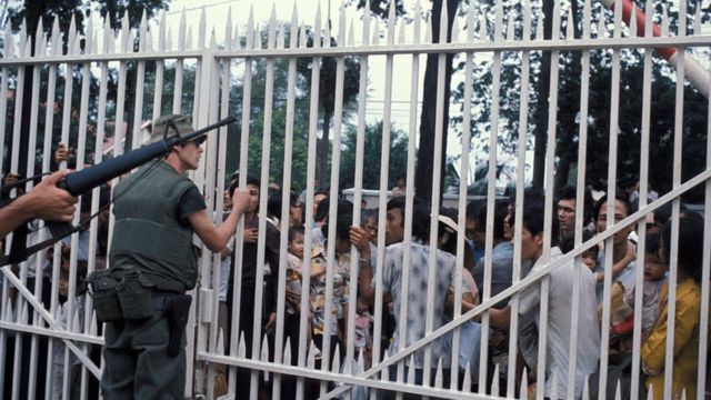 Des Marines américains gardent l'entrée de l'ambassade à Saigon alors qu'une foule de Vietnamiens attend d'être évacuée, le 29 avril 1975