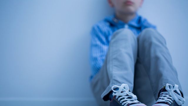 Un niño sentado en el suelo con gesto serio (imagen difuminada(