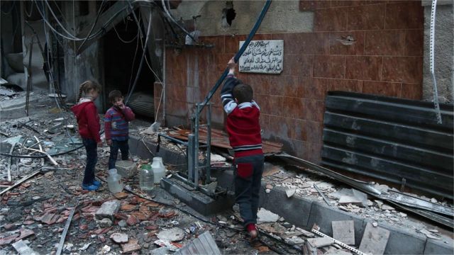Syrian children fill plastic containers at a water pump in Arbin in the rebel-held enclave of Eastern Ghouta on February 25, 2018.