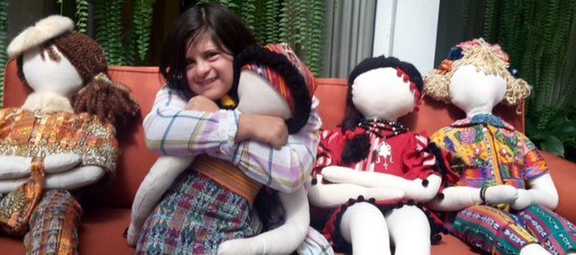 Isabella hugging one of the life-size dolls in her colourful designs of clothing