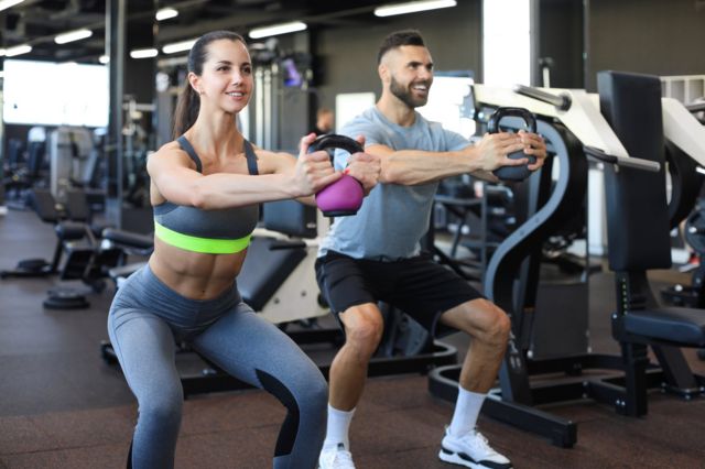 Un hombre y una mujer hacen ejercicios juntos en un gimnasio