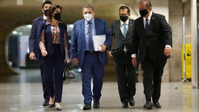 Kassio Nunes caminha de máscara em corredor, com outras pessoas atrás